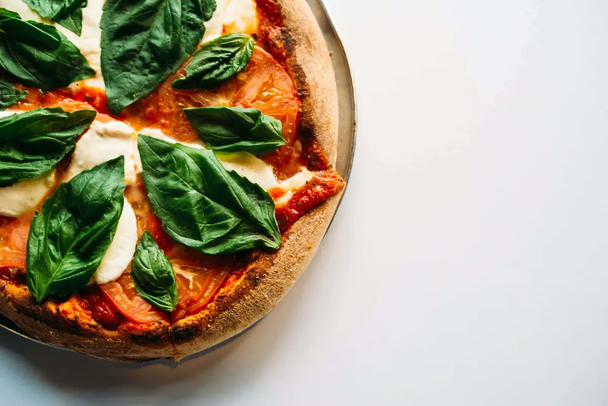 A margherita pizza with fresh mozzarella, tomato and basil on a pan