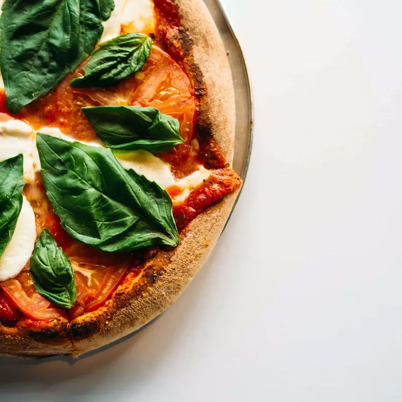A margherita pizza with fresh mozzarella, tomato and basil on a pan